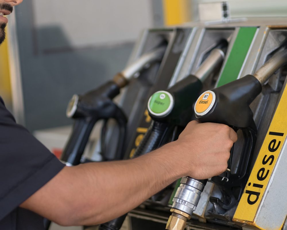 Cropped view of the man preparing refuelling his car at the gas station. Unknown guy hand holding equipment in filling station in city